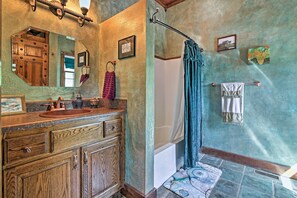 Bathroom features a bathtub, shower curtain, and wooden vanity with a mirror.
