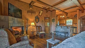 A cozy living room with a fireplace, a television, and rustic decor. - 11 Mi to Dtwn: Murphy Gem w/ Hot Tub & Mtn Views! (Murphy)