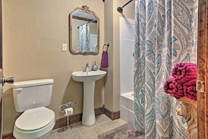 Bathroom features a pedestal sink, toilet, and mirror.