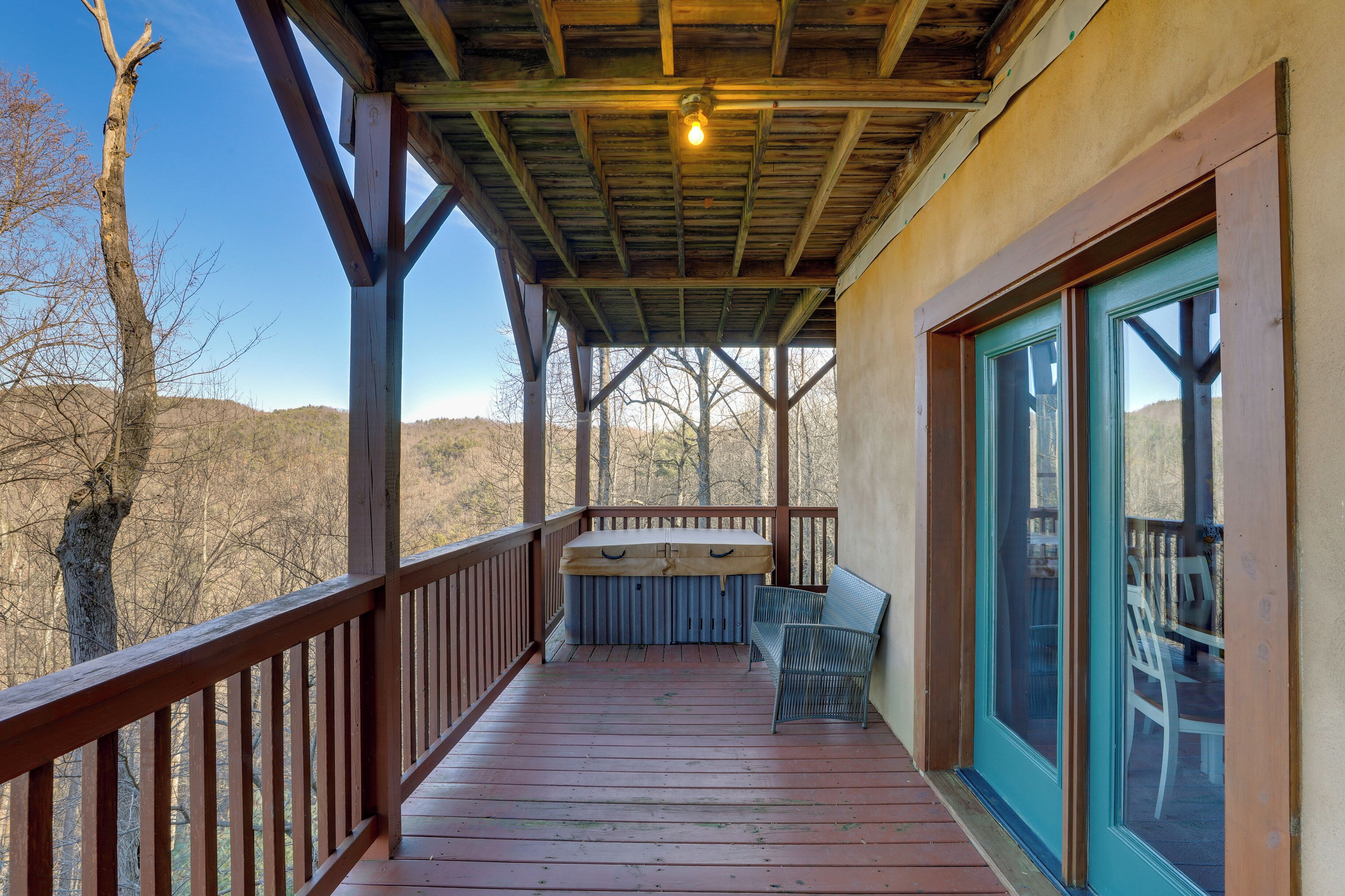 Une véranda couverte avec une balustrade en bois, un banc et une table équipée d’un luminaire.