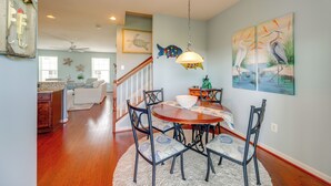 A dining area with a wooden table, chairs, and a hanging light fixture. - Boat Slip & Pool Access: Ocean City Home! (Ocean City)