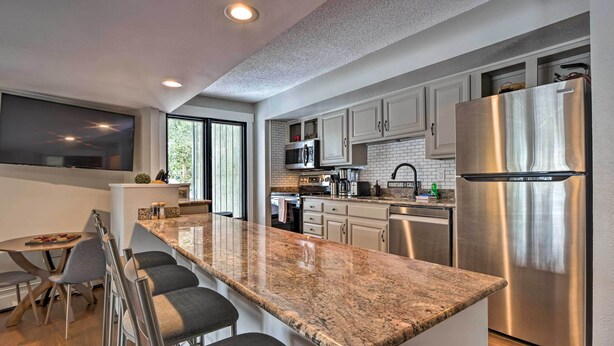 A modern kitchen with granite countertops, stainless steel appliances, and a large island with bar stools. - < 1 Mi to Peak 8: Ski Condo in Breck w/ Mtn Views (Breckenridge)