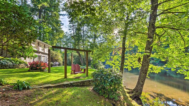 A serene garden with a wooden pergola, a pond, and a stone wall.