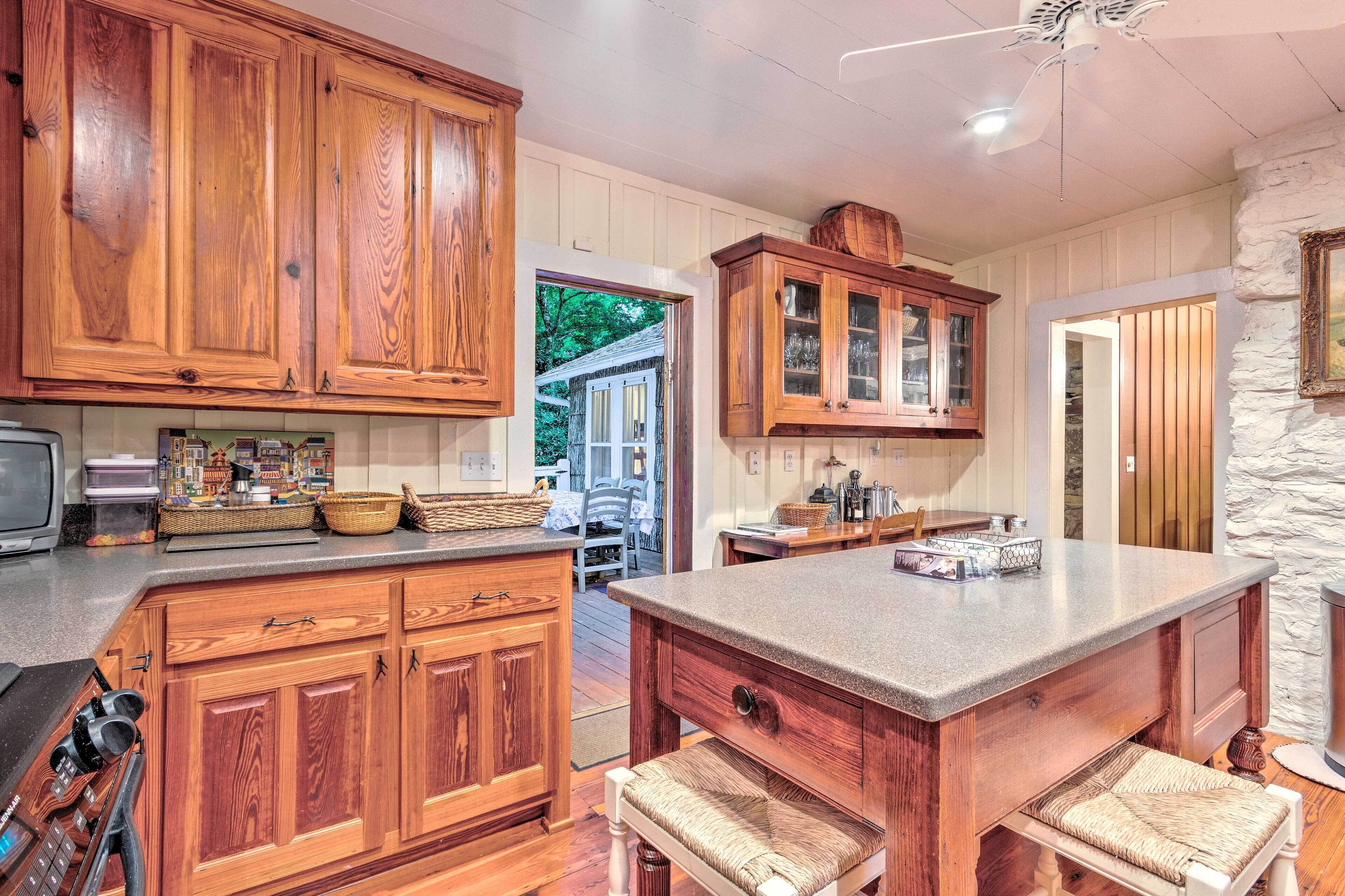 A kitchen with wooden cabinets, a central island with a cushioned bench, and a stone accent wall.