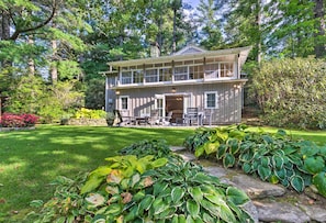 A two-story house with a large front porch, surrounded by lush greenery and a well-maintained garden. - Waterfront Home w/ Boat Dock on Mirror Lake! (Highlands)