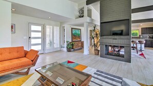 A spacious living area with a modern fireplace, a sofa, and a coffee table. - Palm Springs Oasis w/ Pool & Golf Course Views! (Palm Springs)