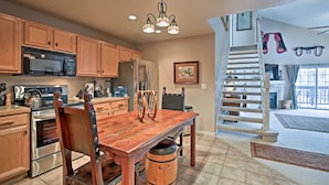 A kitchen with wooden cabinets, stainless steel appliances, a wooden dining table, and a wooden barrel. - Steamboat Springs Condo w/ Hot Tub & Ski Bus! (Steamboat Springs)