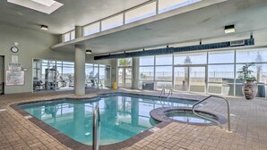 An indoor swimming pool with clear glass walls, a tiled floor, and a view of the outside.