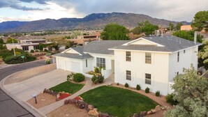 A two-story house with a garage, a driveway, and a well-maintained lawn. - Family&Groups, 5br, Sleep 12, Pool/Hot tub/Firepit (Albuquerque)