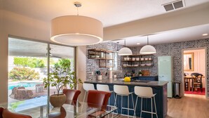 A modern kitchen with a central island, bar stools, and a dining area with a glass table. - Family&Groups, 5br, Sleep 12, Pool/Hot tub/Firepit (Albuquerque)