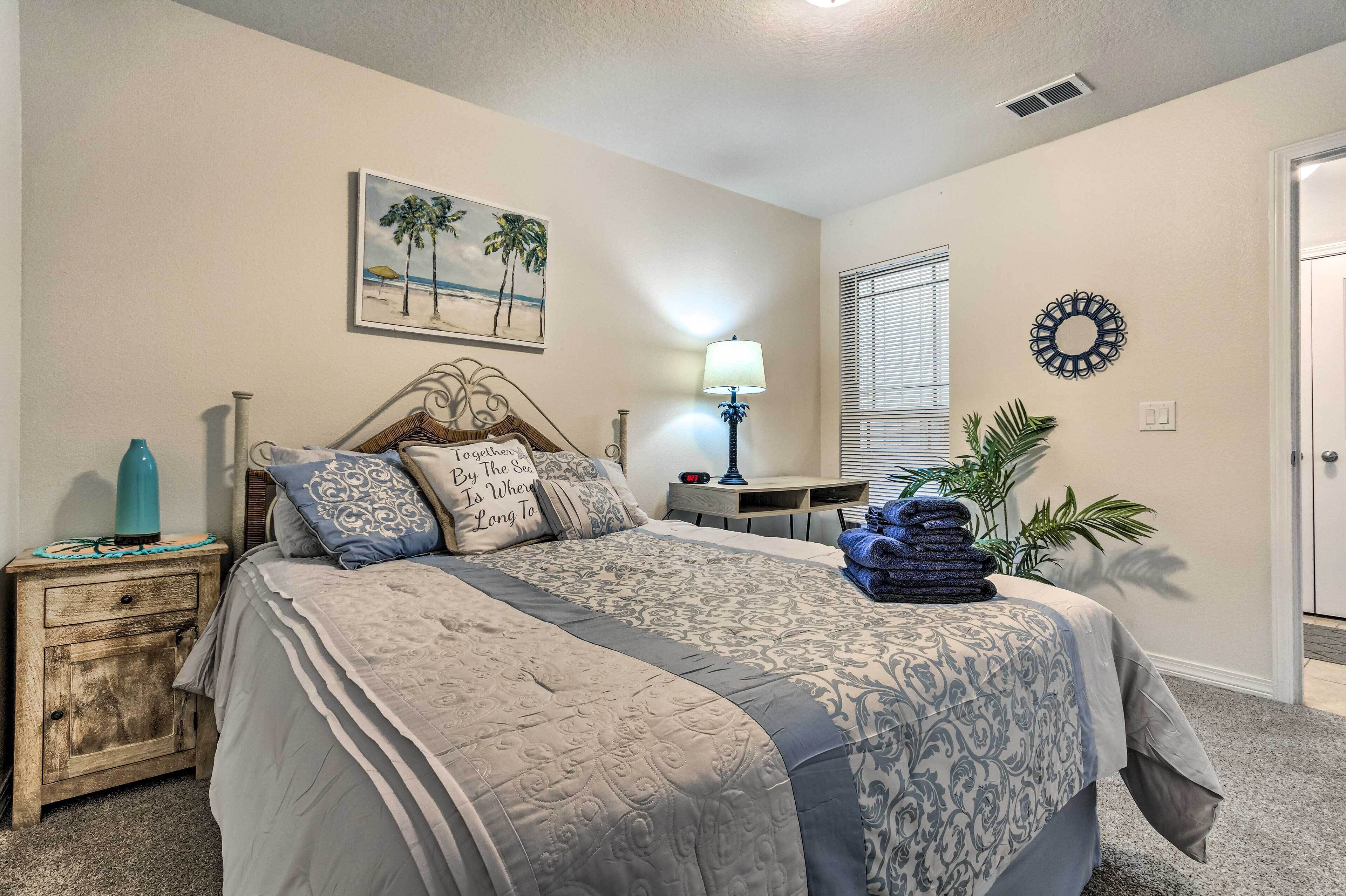 A bedroom with a bed, nightstand, lamp, and a painting on the wall.