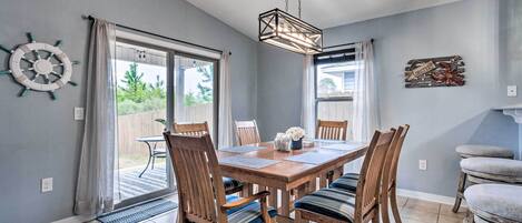 A dining area with a wooden table, chairs, and a hanging light fixture.