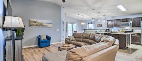 A spacious living room with a large sectional sofa, a coffee table, and a ceiling fan.