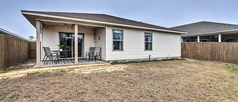 A single-story house with a covered patio, a fenced backyard, and a wooden fence.