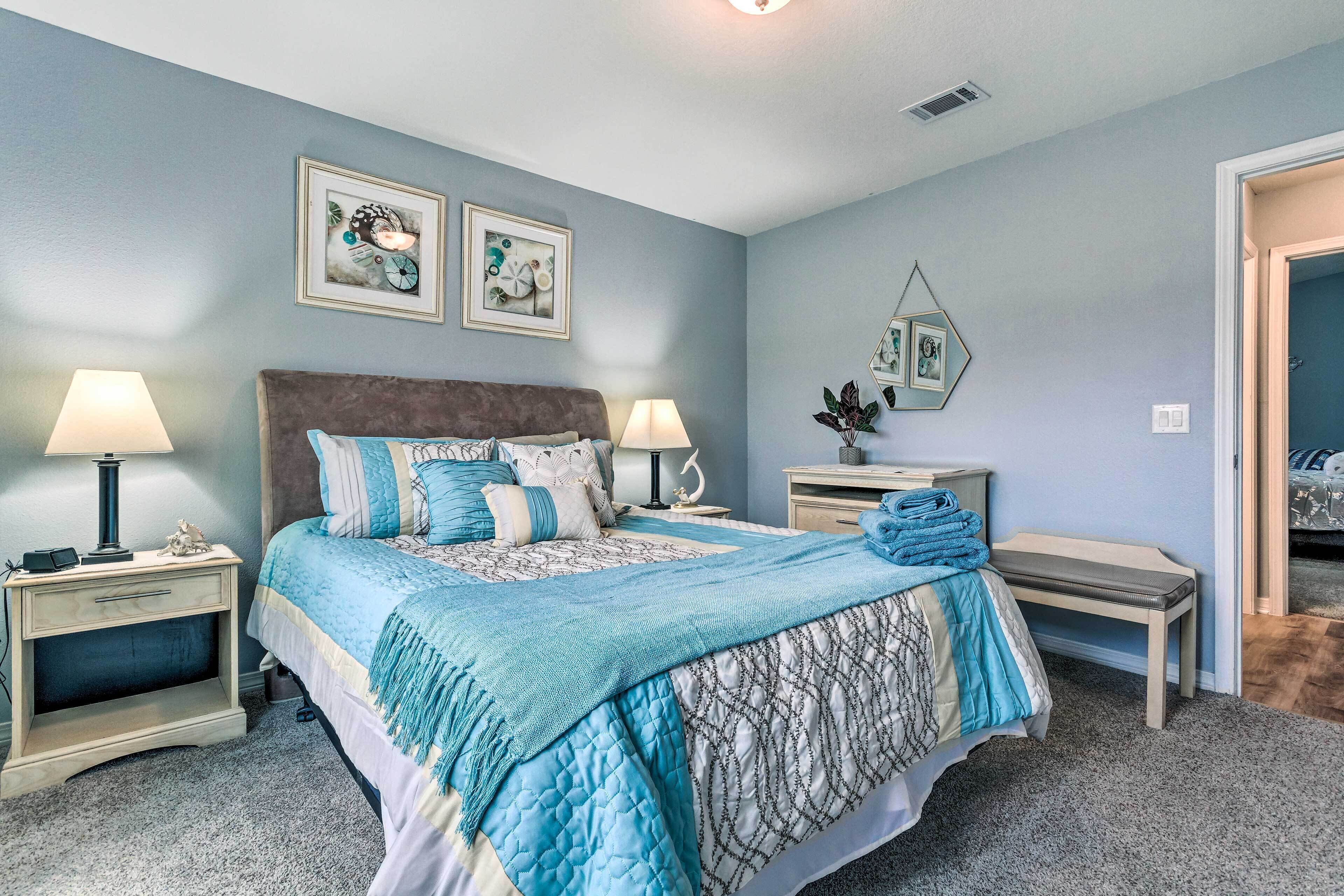 A bedroom with a bed, two bedside tables, a nightstand, and a mirror on the wall.