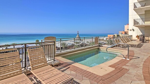 A pool area with lounge chairs and a view of the ocean. - Chic Panama City Beach Condo w/ Pool & Gulf Views (Panama City Beach)