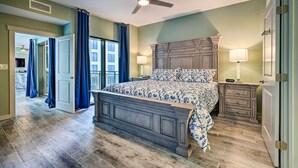 A bedroom with a large bed, a ceiling fan, a nightstand, and a dresser. - Chic Panama City Beach Condo w/ Pool & Gulf Views (Panama City Beach)