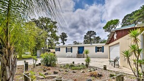 A two-story mobile home with a blue door, surrounded by a landscaped garden with various plants and a rope barrier. - Waterfront Home w/ Boat Dock & Large Porch! (Georgetown)