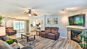A spacious living room with a fireplace, leather sofas, a dining area, and a kitchen in the background. - Waterfront Home w/ Boat Dock & Large Porch! (Georgetown)