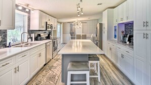 A modern kitchen with white cabinetry, a central island, and a chandelier. - Waterfront Home w/ Boat Dock & Large Porch! (Georgetown)