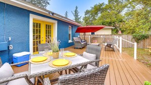 A patio with wicker furniture, a table with yellow placemats, and a red umbrella.