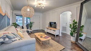 A living room with a sofa, coffee table, TV, and decorative plants.