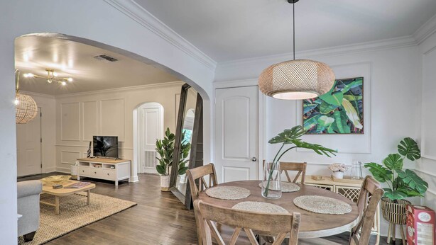 A dining area with a round wooden table, woven placemats, and a hanging woven light fixture.