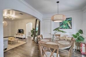A dining area with a round wooden table, woven placemats, and a hanging woven light fixture. - St Petersburg Escape w/ Fenced Yard + Games! (St. Petersburg)
