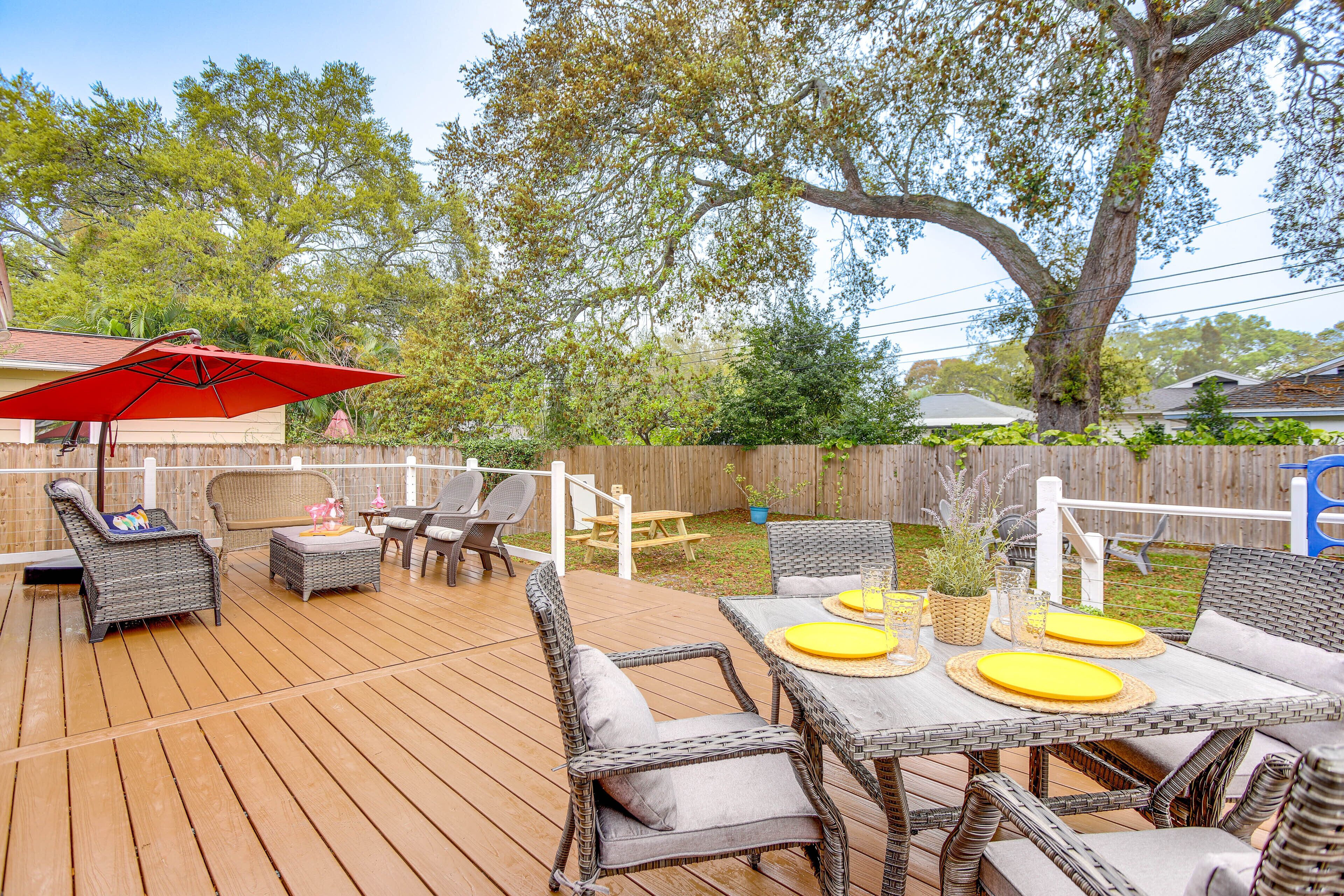 A wooden deck with wicker furniture, including chairs and a table with yellow placemats.