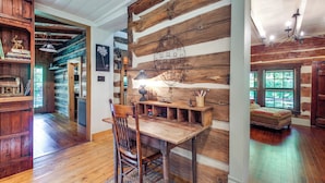 A rustic interior with a wooden dining table, a chair, and a bookshelf. - Restored Buchanan Log Cabin on 9-mile Creek! (Buchanan)