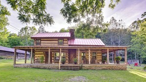 A log cabin with a covered porch and a stone foundation. - Restored Buchanan Log Cabin on 9-mile Creek! (Buchanan)