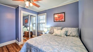 Un dormitorio con cama, ventilador de techo y ventana con persianas.