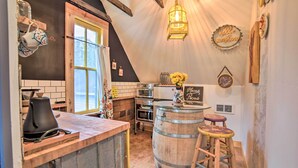 Une cuisine chaleureuse avec un comptoir-bar en bois, une machine à café, une bouilloire, un tabouret en bois et une lanterne.