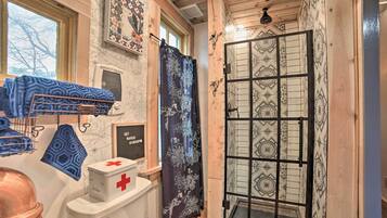 A bathroom with a shower, a towel rack, a toilet, and a decorative wall.