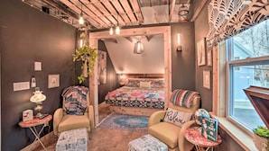 Une chambre confortable avec un lit, deux fauteuils, une petite table et une fenêtre donnant sur un beau paysage.