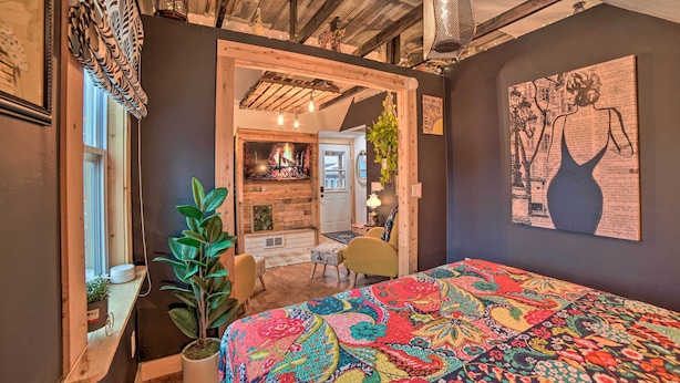 Une pièce chaleureuse avec une couvre-lit aux couleurs vives, un plafond en bois et une décoration rustique.