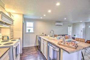 Una cocina moderna con una isla central, horno integrado y electrodomésticos de acero inoxidable.