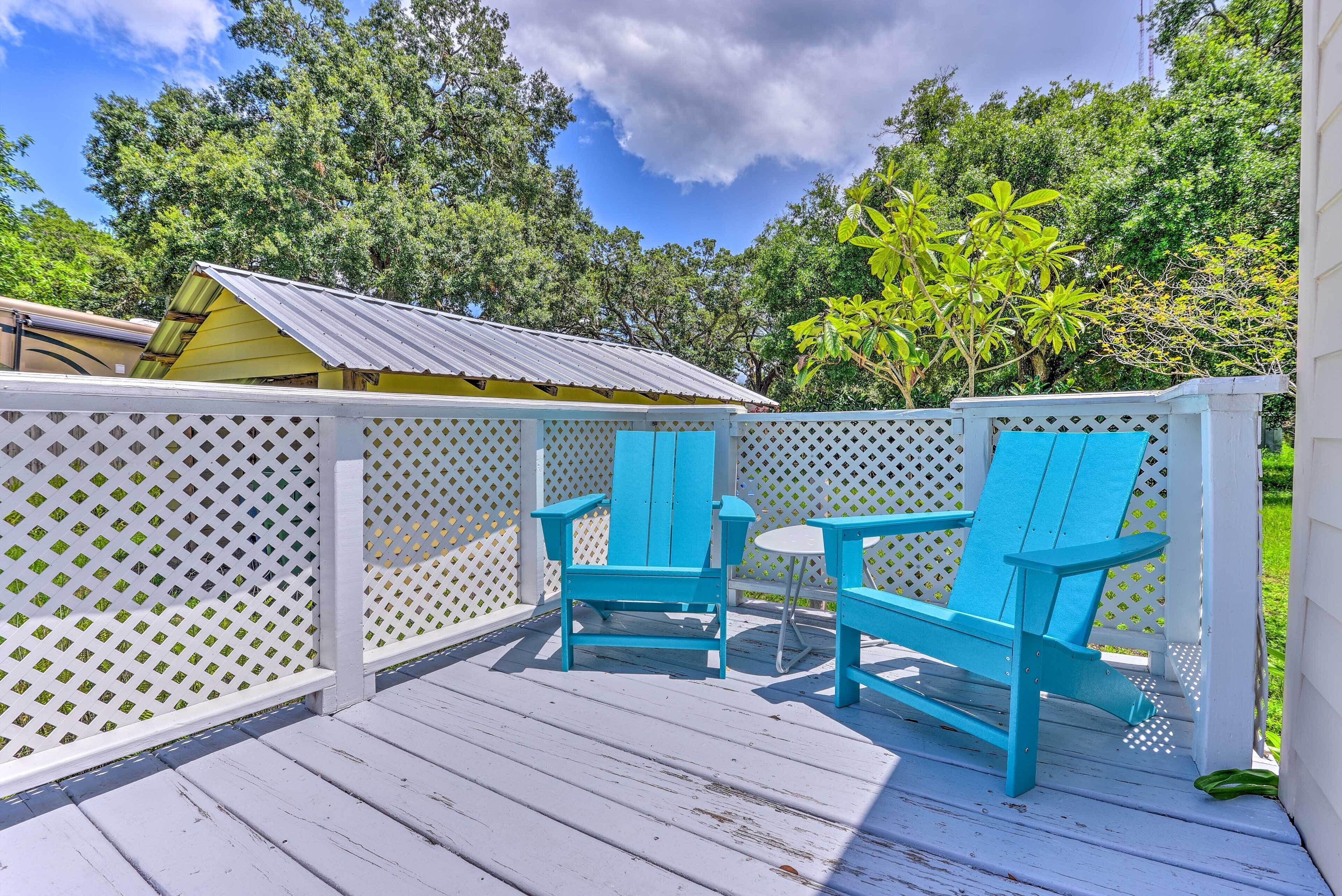 Une terrasse en bois avec deux fauteuils Adirondack turquoise et une petite table ronde.