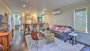 Eine moderne Küche mit Kochinsel, Essbereich mit Stühlen, Sofa mit Kissen und einem kleinen runden Tisch.