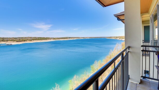 A balcony with a view of a calm sea and distant shoreline. - Top-floor Lake-view Condo w/ Boat Dock Access (Lakeway)