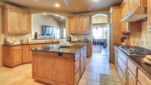 A spacious kitchen with wooden cabinets, a large island, and a central island with a stove. - Top-floor Lake-view Condo w/ Boat Dock Access (Lakeway)