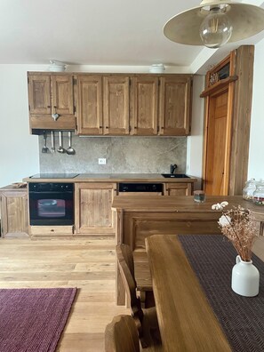 A kitchen with wooden cabinets, a built-in oven, and a dining area with a table and chairs.