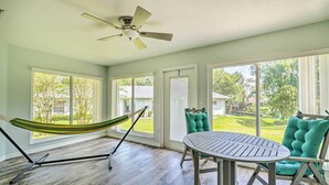 A room with a hammock, a round table, and a teal chair.