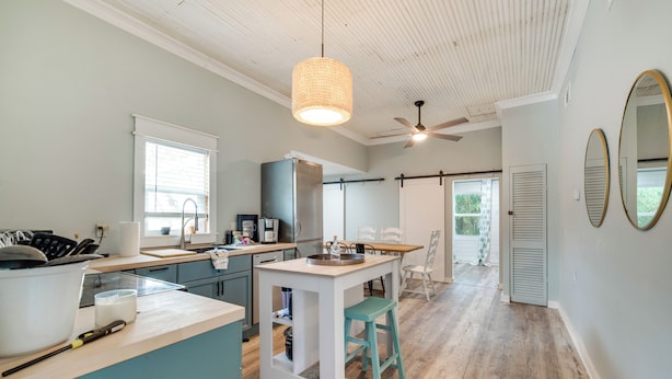 Una cocina con una isla central, un ventilador de techo y un comedor con sillas.