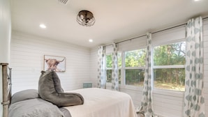 Un dormitorio con una cama, una ventana con cortinas, una lámpara en el techo y un cuadro en la pared.