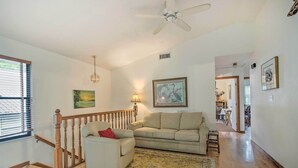 A spacious living room with a wooden staircase, a beige sofa, a small armchair, and a yellow patterned rug. - Waterfront Inglis Getaway w/ Dock: 5 Mi to Gulf (Inglis)
