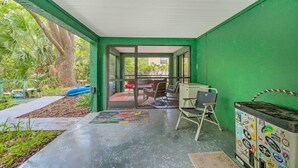A covered outdoor area with a green wall, a glass door leading outside, a colorful mat, a metal chair, and a cabinet with stickers. - Waterfront Inglis Getaway w/ Dock: 5 Mi to Gulf (Inglis)