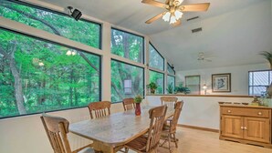 A dining area with a large wooden table and chairs, large windows with a forest view, ceiling fans, and wooden cabinets. - Waterfront Inglis Getaway w/ Dock: 5 Mi to Gulf (Inglis)