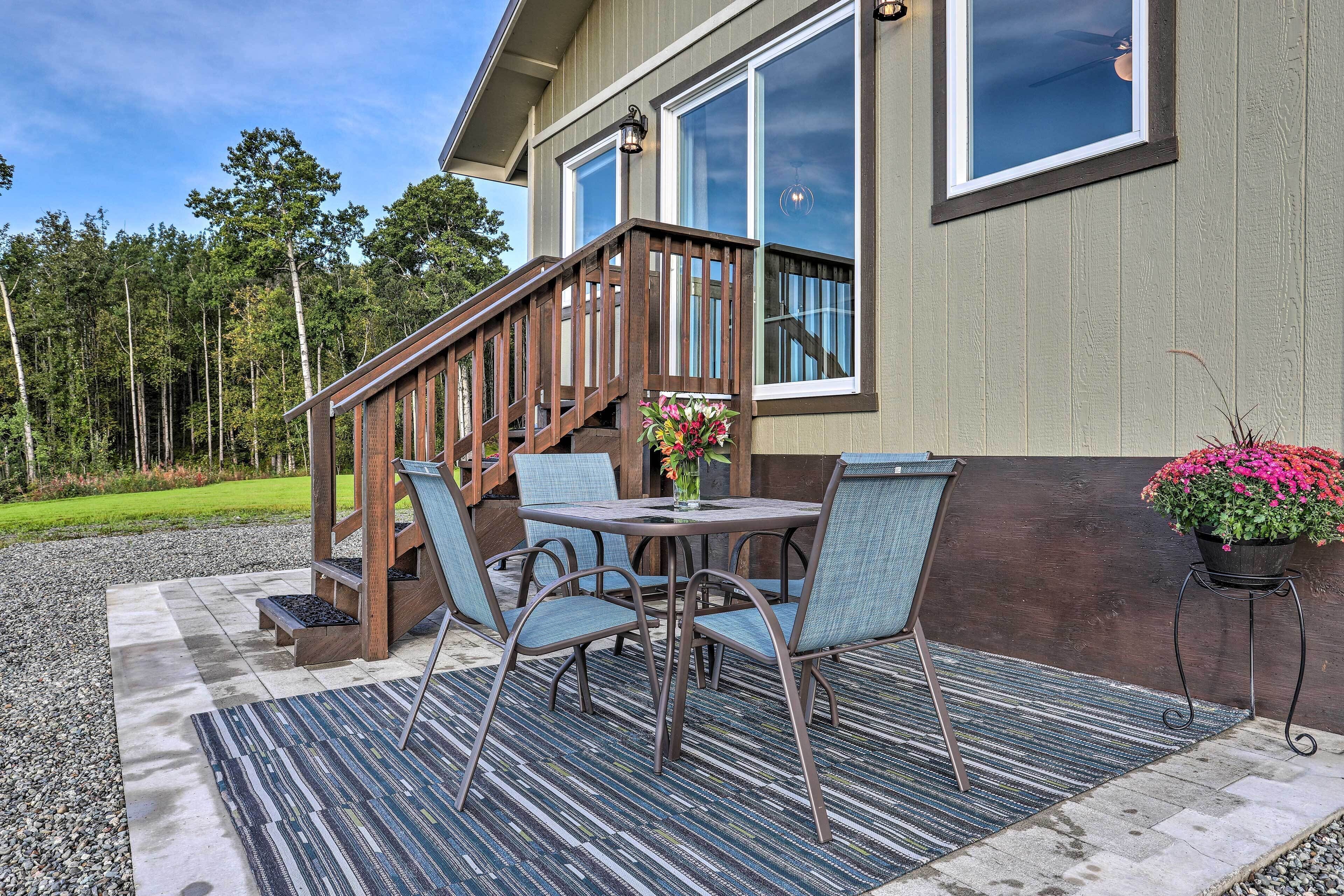 A patio with a table and chairs, a wooden staircase, and a railing.