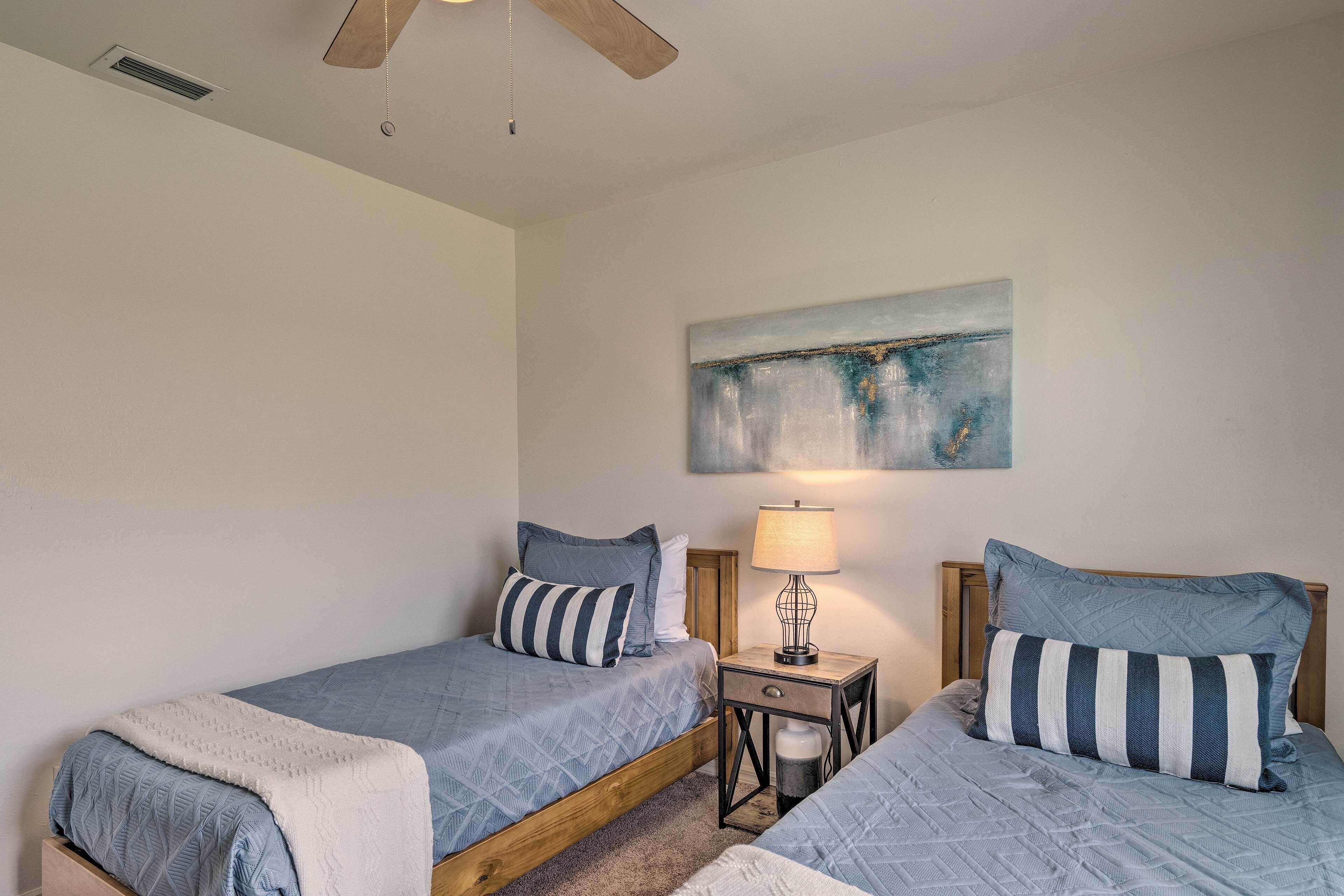 A bedroom with two single beds, a nightstand with a lamp, and a painting on the wall.